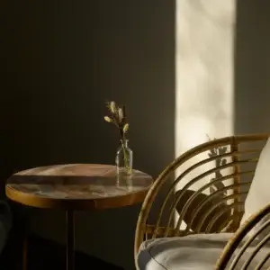 Stemningsfull belysning på marmorbord og rottingstol, boligstyling detaljer.